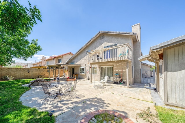 rear view of house featuring a balcony, a fenced backyard, and a patio area