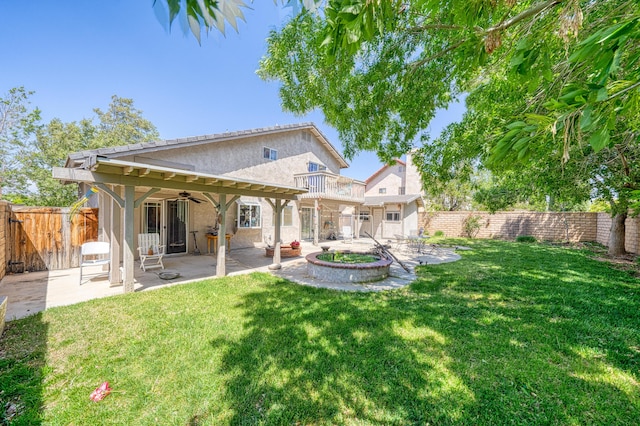 rear view of house featuring stucco siding, a fenced backyard, a lawn, a ceiling fan, and a patio