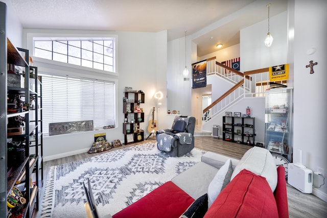 living area with baseboards, a high ceiling, wood finished floors, and stairway