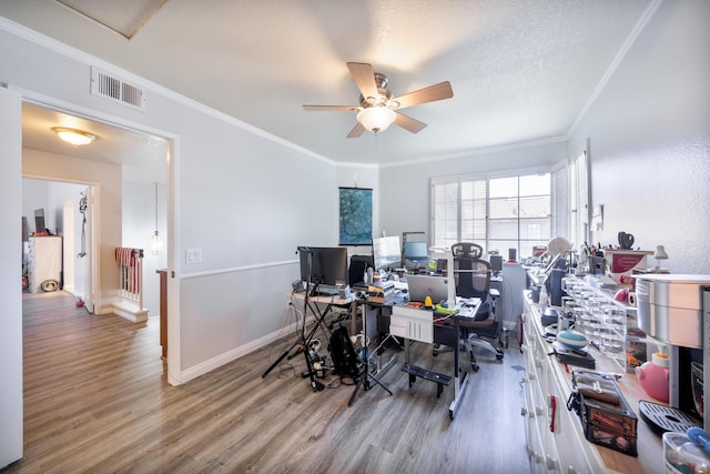 office space with a ceiling fan, visible vents, wood finished floors, baseboards, and ornamental molding