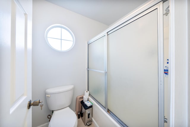 bathroom featuring enclosed tub / shower combo and toilet