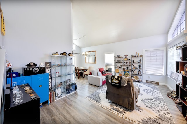 living area with wood finished floors, a notable chandelier, and vaulted ceiling