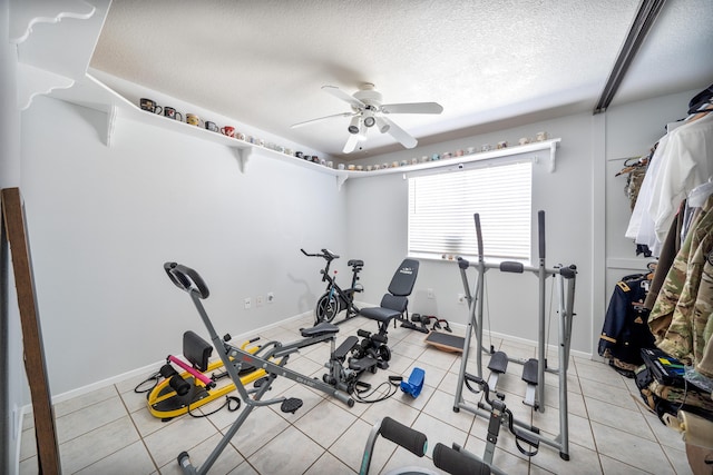 exercise room featuring light tile patterned floors, ceiling fan, and a textured ceiling