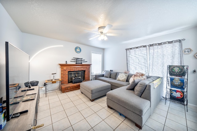 living room featuring a textured ceiling, ceiling fan, a brick fireplace, and light tile patterned flooring