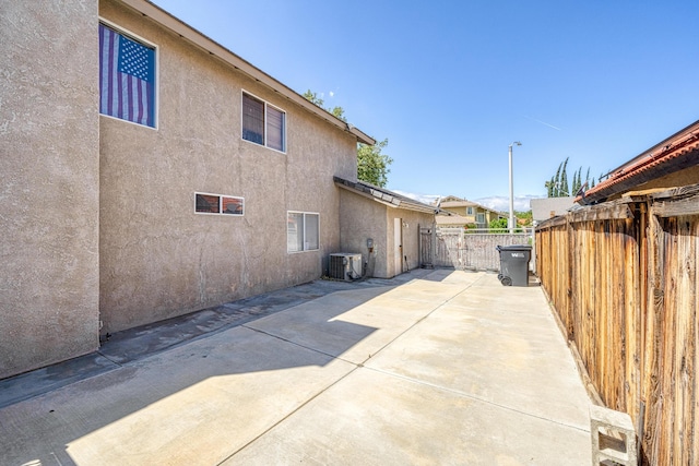 view of home's exterior featuring central AC unit, a patio area, stucco siding, and fence