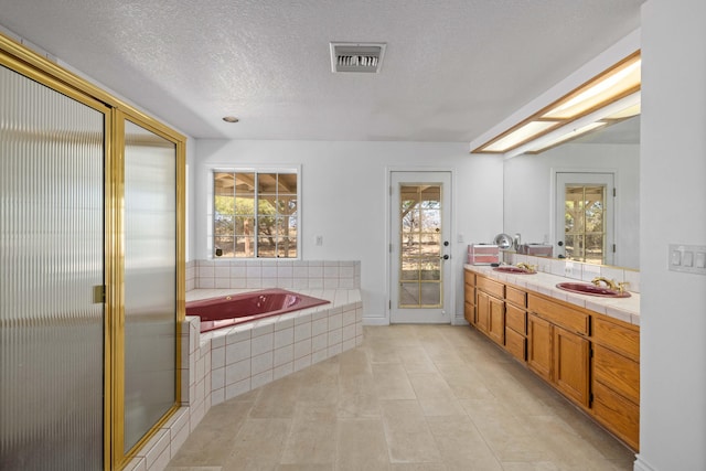bathroom featuring double vanity, a garden tub, a textured ceiling, visible vents, and a shower stall
