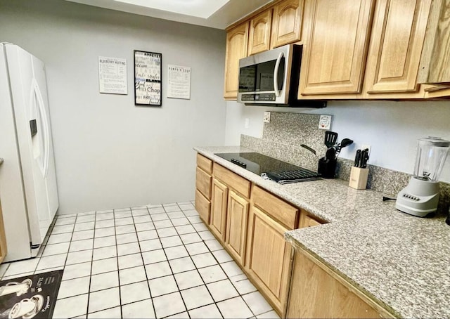 kitchen featuring light tile patterned floors, black electric stovetop, light countertops, white fridge with ice dispenser, and stainless steel microwave