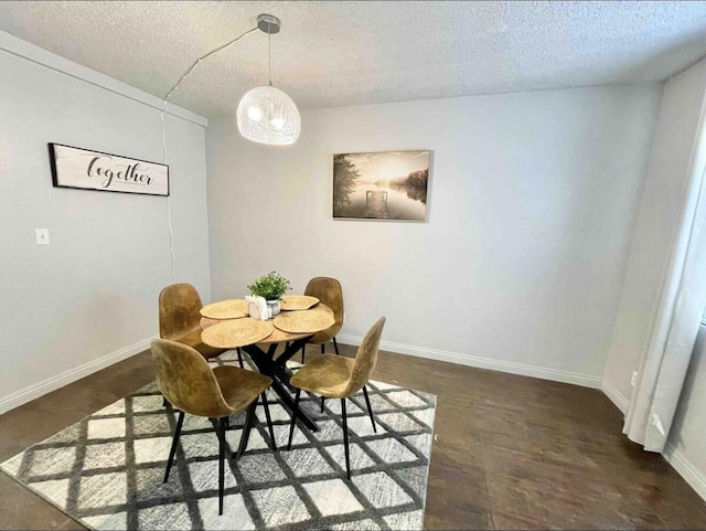 dining space with dark wood-type flooring, a chandelier, a textured ceiling, and baseboards