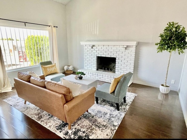 living area featuring a fireplace, baseboards, and wood finished floors