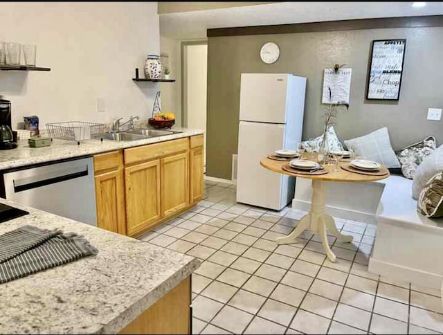 kitchen featuring light tile patterned floors, a sink, stainless steel dishwasher, freestanding refrigerator, and open shelves