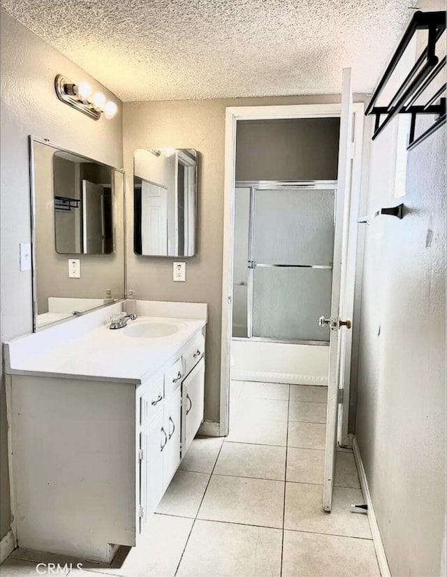 bathroom featuring a textured ceiling, shower / bath combination with glass door, vanity, and tile patterned floors