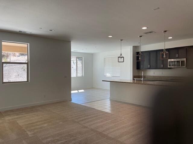 kitchen featuring decorative light fixtures, light colored carpet, dark brown cabinetry, and sink