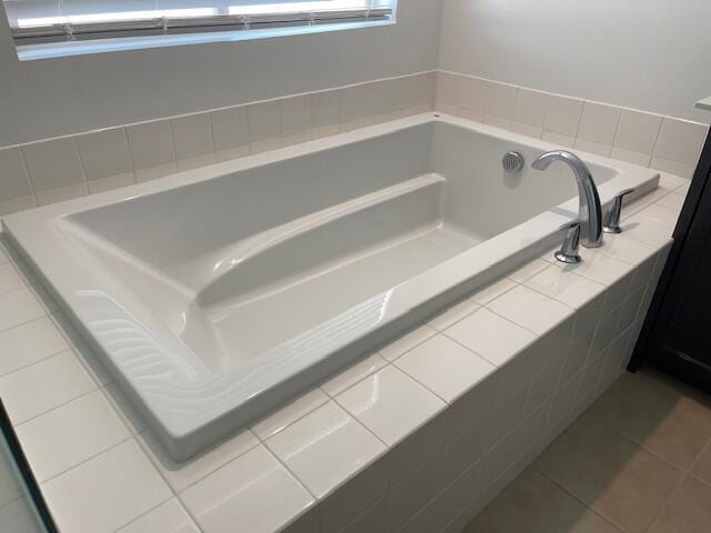 bathroom with tile patterned floors, tiled bath, and vanity