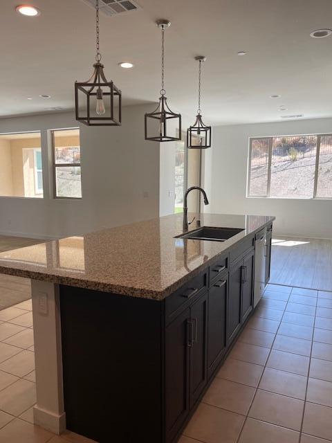 kitchen featuring plenty of natural light, light tile patterned flooring, light stone counters, and sink