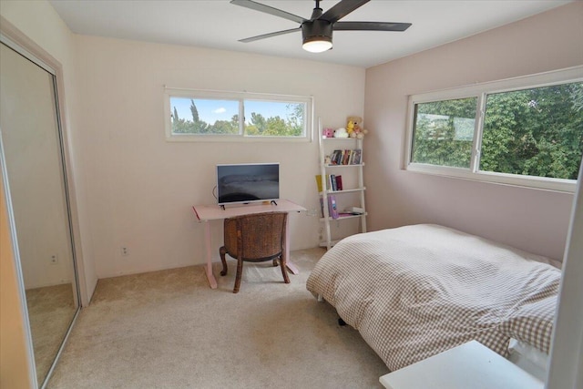 bedroom featuring ceiling fan, light carpet, a closet, and multiple windows