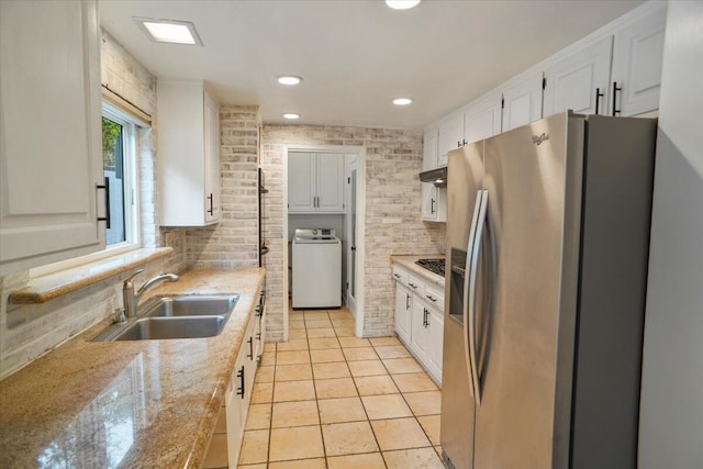 kitchen with washer / dryer, stainless steel fridge, white cabinets, and sink