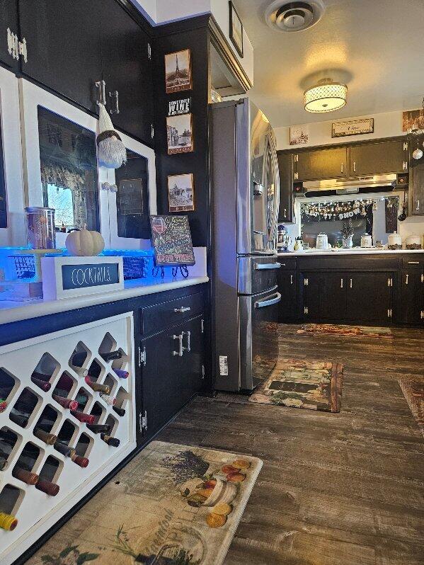 bar with wood finished floors, visible vents, under cabinet range hood, and stainless steel fridge with ice dispenser