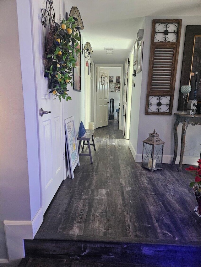 corridor with baseboards and wood finished floors