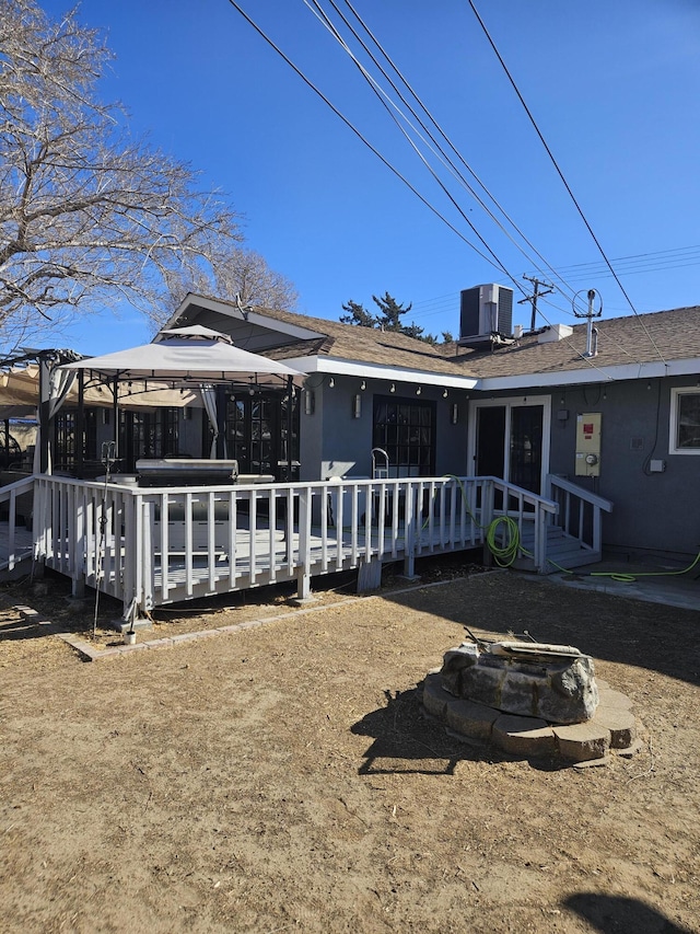 back of house with central AC unit, a gazebo, a deck, an outdoor fire pit, and roof with shingles