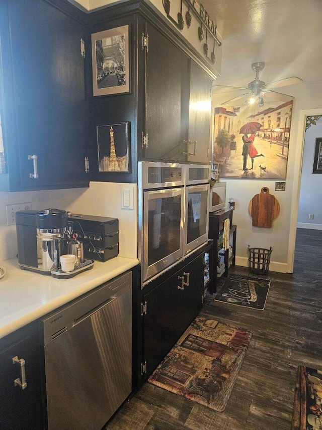 kitchen featuring stainless steel dishwasher, a ceiling fan, light countertops, baseboards, and dark wood-type flooring