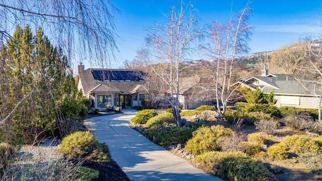 view of front of property with a chimney and solar panels