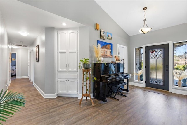 foyer entrance with lofted ceiling, baseboards, and wood finished floors