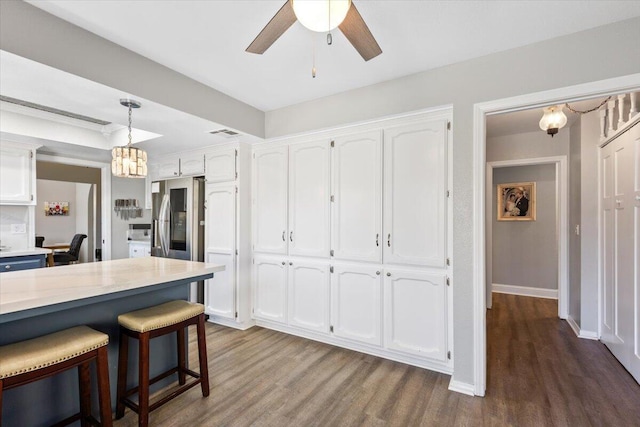 kitchen with decorative light fixtures, stainless steel refrigerator with ice dispenser, white cabinets, wood finished floors, and a kitchen breakfast bar