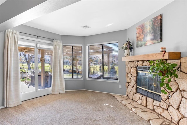 living area with carpet, a healthy amount of sunlight, visible vents, and a fireplace