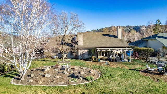 rear view of house featuring a yard, a chimney, and a patio