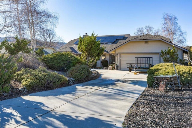 view of front facade with driveway, an attached garage, and solar panels