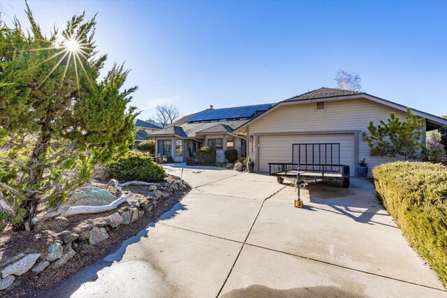 view of front of home featuring driveway, a garage, and solar panels