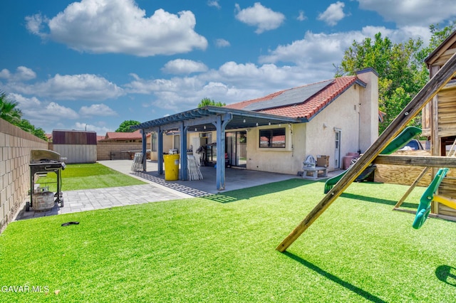1027 James Ct, Lancaster, CA 93535 - rear view of property with a shed, stucco siding, a fenced backyard, roof mounted solar panels, and a patio area