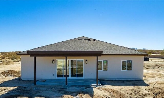 rear view of property with a shingled roof, a patio, and stucco siding