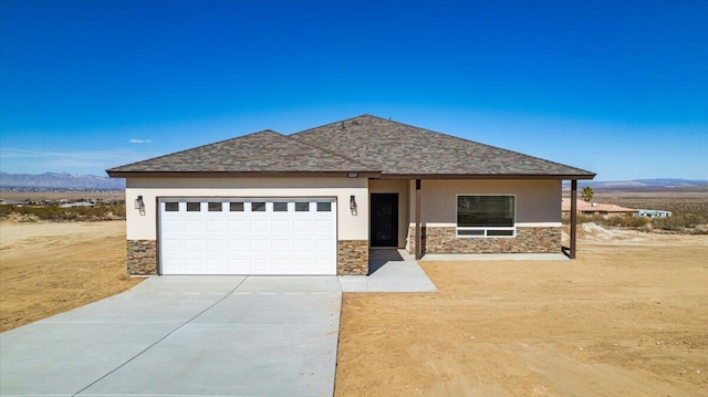 view of front of home featuring stone siding, a mountain view, driveway, and stucco siding