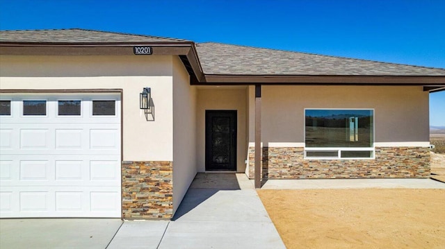 doorway to property with an attached garage, stone siding, roof with shingles, and stucco siding