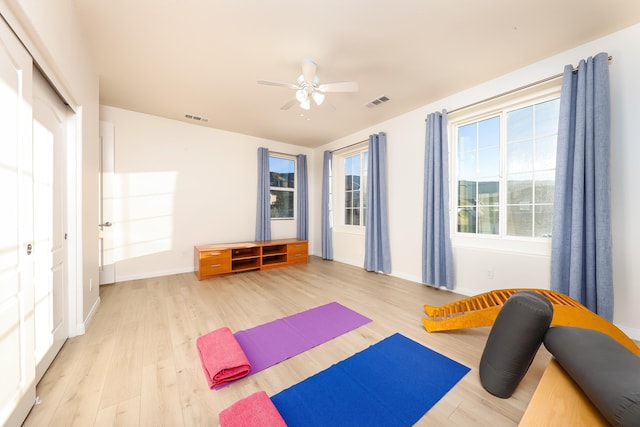 exercise area with ceiling fan and light hardwood / wood-style flooring