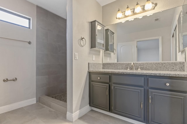 full bath with visible vents, baseboards, tile patterned floors, a tile shower, and vanity