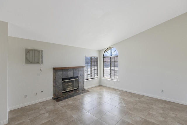 unfurnished living room featuring a tile fireplace, vaulted ceiling, baseboards, and light tile patterned floors