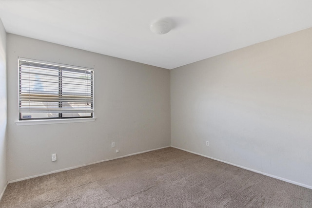 carpeted empty room featuring baseboards