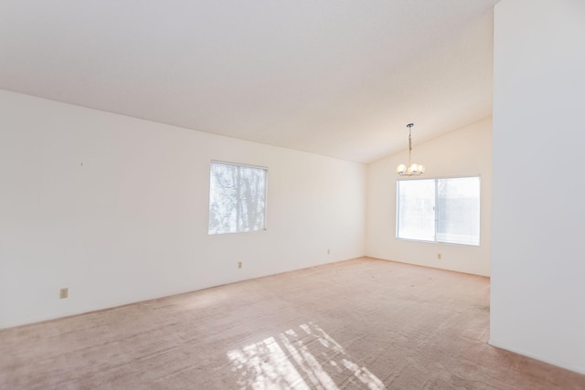 empty room featuring lofted ceiling, light colored carpet, and a chandelier