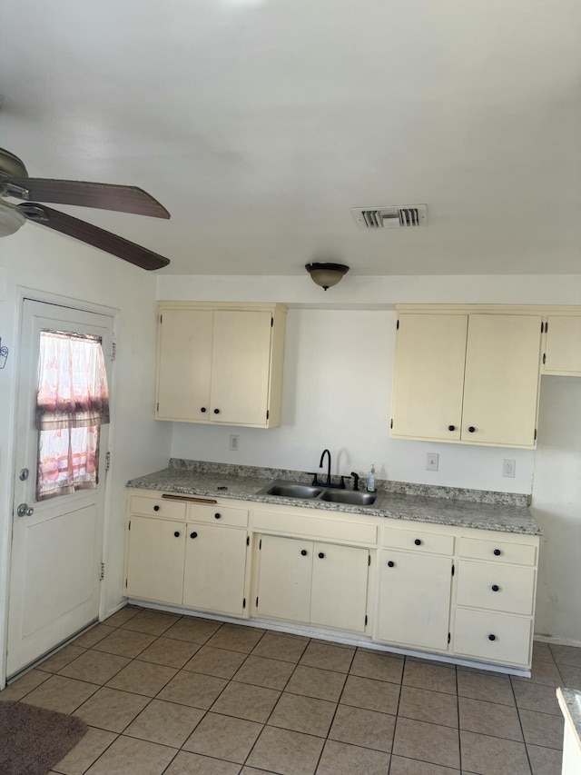 kitchen with light tile patterned flooring, cream cabinets, ceiling fan, and sink