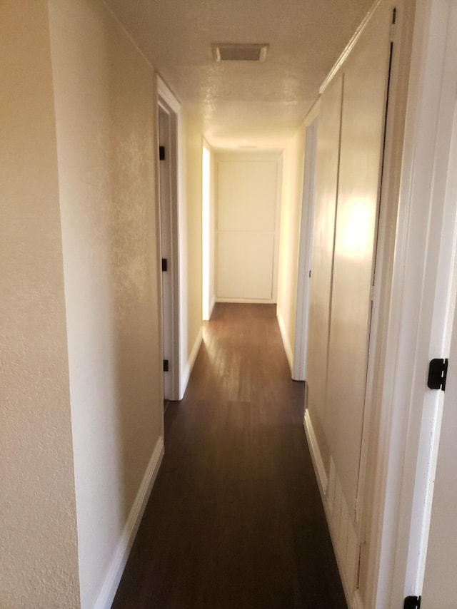 hall with a textured ceiling and dark hardwood / wood-style floors