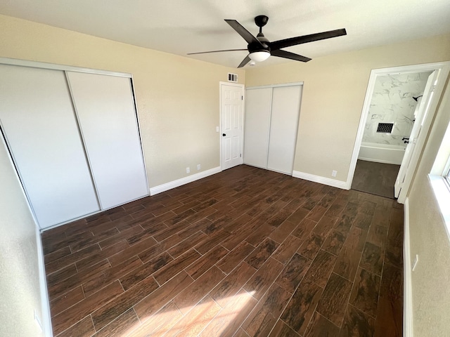 unfurnished bedroom featuring ceiling fan, connected bathroom, and two closets