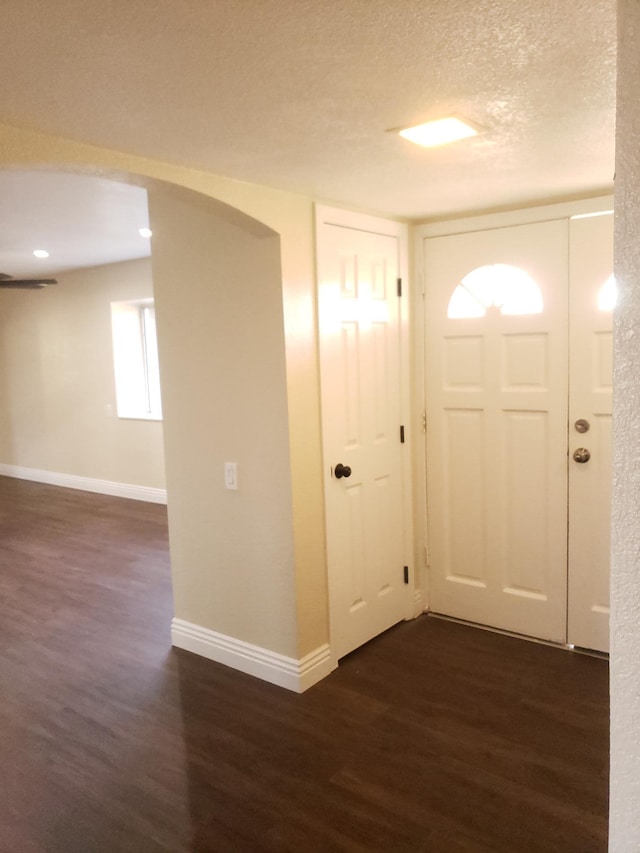 entryway with dark wood-type flooring and a textured ceiling