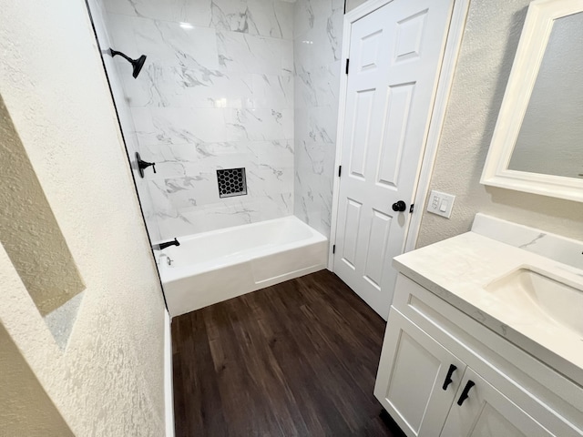 bathroom with hardwood / wood-style floors, vanity, and tiled shower / bath