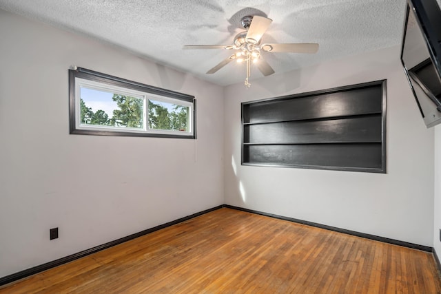 empty room featuring ceiling fan, wood-type flooring, and a textured ceiling