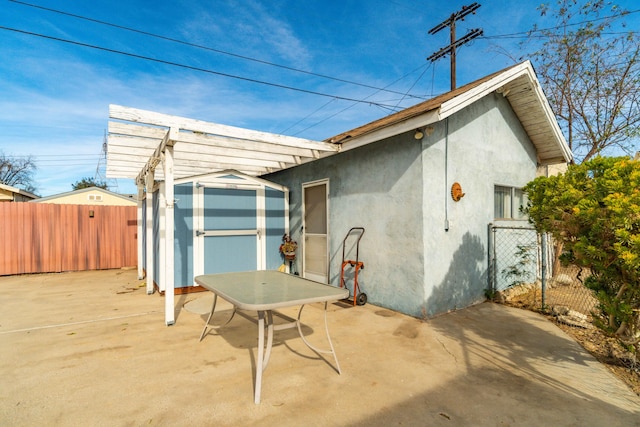 rear view of house featuring a pergola, a shed, and a patio area