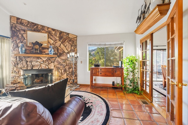 tiled living room with a stone fireplace and french doors