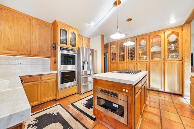 kitchen featuring tasteful backsplash, stainless steel appliances, light tile patterned floors, a center island, and hanging light fixtures