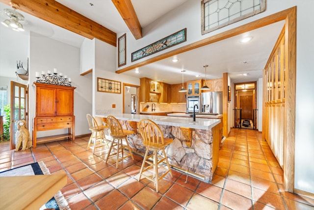 kitchen with pendant lighting, a breakfast bar, appliances with stainless steel finishes, beamed ceiling, and kitchen peninsula